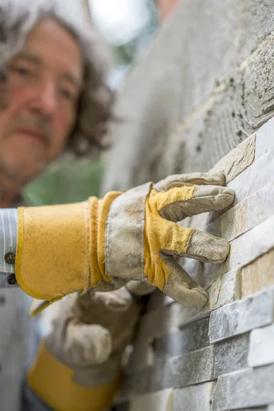 Vista a basso angolo del lavoratore maschile premendo una piastrella ornamentale in un — Foto Stock