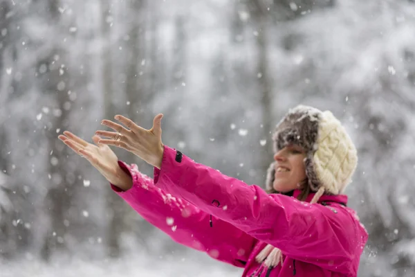 Happy young woman wearing warm hat and bright pink jacket standi — Stock Photo, Image