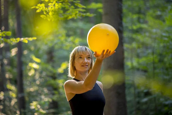 Jeune blonde pilates stagiaire tenant une boule jaune — Photo