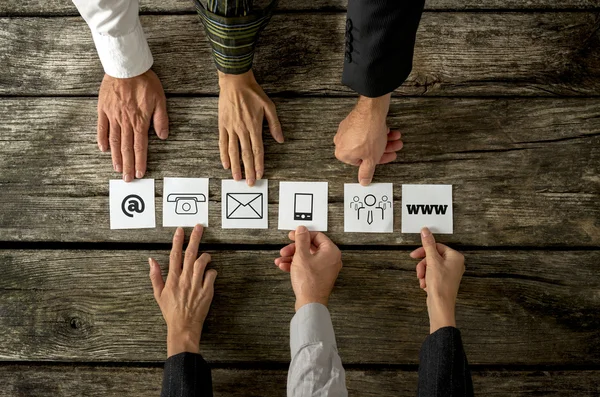 Six people placing white cards with various contact icons in a r — Stock Photo, Image