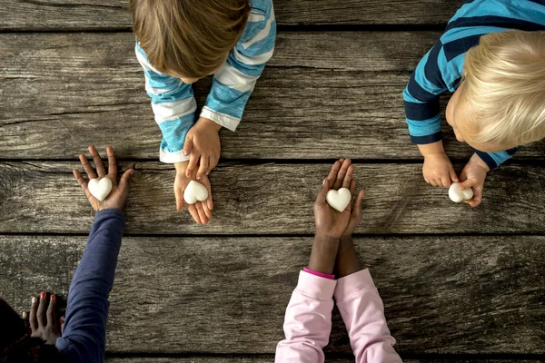 Top view dari empat anak-anak dari ras campuran masing-masing memegang marmer h — Stok Foto