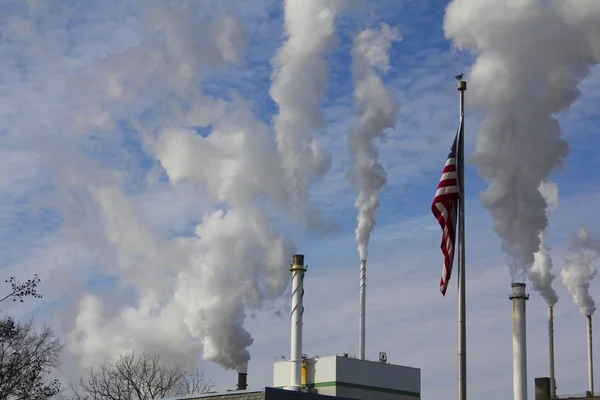 American Flag Against Backdrop of Factory Smokestacks Stock Photo