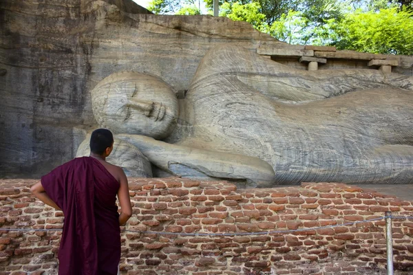 Sri Lankas munk som tittar på stenhuggna liggande Buddha — Stockfoto