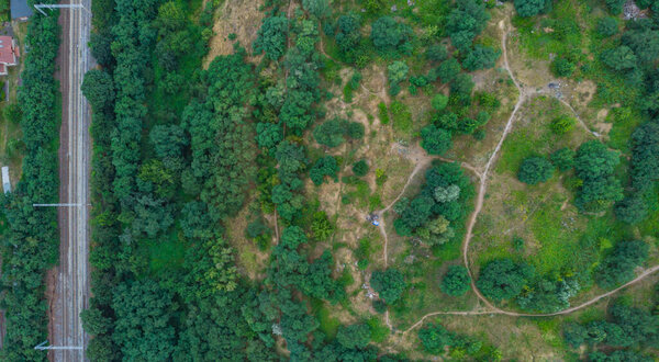 Top down aerial look to paths in park on hill and train rails on side