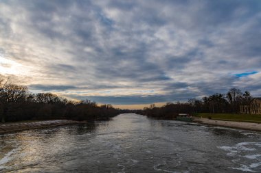 Etrafı ağaçlarla çevrili, Odra nehri üzerindeki bulutlu bir arazi.