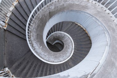 Paslı metal parmaklıkları olan eski beton sarmal merdiven.