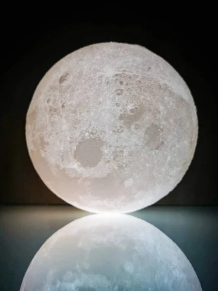 Small white 3d printed moon lamp reflected on glass