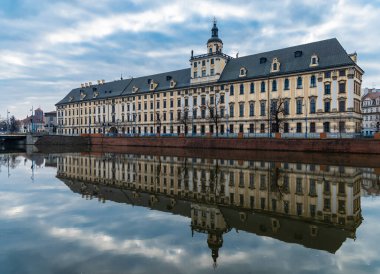 Wroclaw, Polonya - 19 Mart 2020 Wroclaw Üniversitesi Cephesi Bulutlu bir sabahta Sessiz Odra Nehri 'ne yansıdı