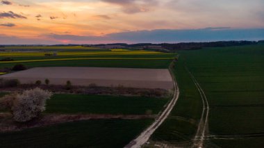 Hava aracı gün batımında yeşil ve sarı tarlalara bakıyor.