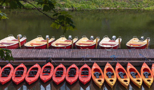 Wroclaw, Poland - May 03 2020: Row of kayaks and motorboats near wooden bridge
