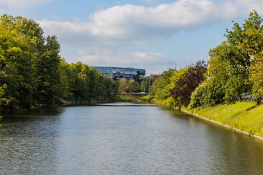 Wroclaw, Polonya - 26 Mayıs 2020: Ağaç ve çalılarla çevrili küçük şehir hendeği ve sonunda alışveriş merkezi