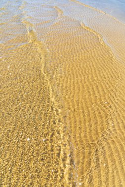 Baltık Denizi 'nin sakin kıyılarında berrak, sığ sularda görülen karmaşık kum dalgaları soyut desenler oluşturur.