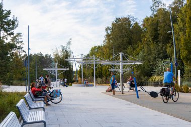 Swinoujscie, Polonya - 21 Eylül 2024: Swinoujcie City 'de Ağaçlar Arasında Yürüyen İnsanlar ve Modern Banklarla Güneşli Gezinti