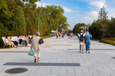 Swinoujscie, Polonya - 21 Eylül 2024: Swinoujcie City 'de Ağaçlar Arasında Yürüyen İnsanlar ve Modern Banklarla Güneşli Gezinti