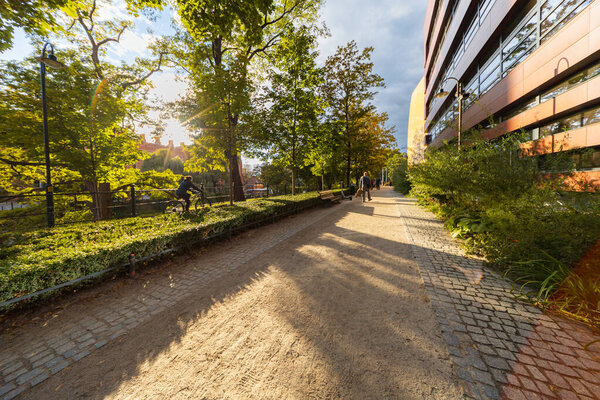 Вроцлав, Польша - 29 сентября 2024 года: Солнечный путь между зданием Национального музыкального форума и историческим рвом во Вроцлаве, где люди наслаждаются осенним днем
