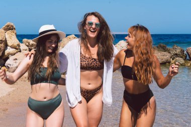 Sahilde gezinen bir grup güzel genç kadın. Arkadaşlar sahilde yürüyor ve bir yaz günü gülüyorlar..