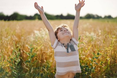 Küçük çocuk gözlerini kapadı ve ellerini havaya kaldırdı.