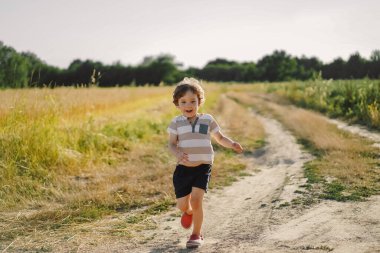 Mutlu çocuk doğada yaz mevsiminde çayırda koşuyor..