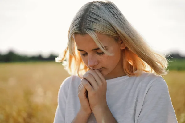少女は目を閉じて畑で祈っていた 信仰のための祈りの概念に折り畳まれた手 — ストック写真