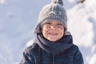 Yüzünde kırmızı kalpler olan neşeli çocuk. Aşk konsepti