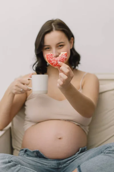 Pregnancy and nutrition. Pregnant woman enjoying donuts and tea. — Stock Photo, Image