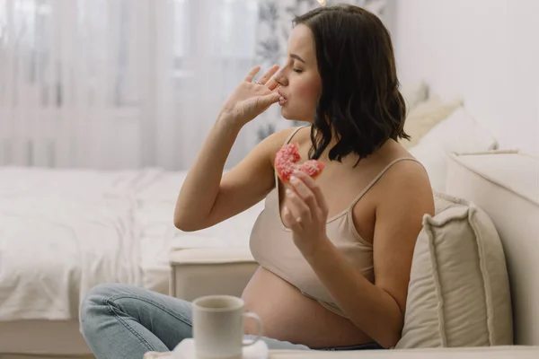 Embarazo y nutrición. Mujer embarazada disfrutando de donas y té. — Foto de Stock