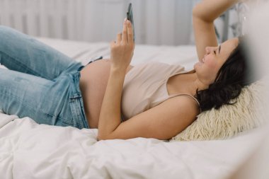 Cep telefonu kullanan mutlu ve çekici hamile kadın. Hamile Kadın.