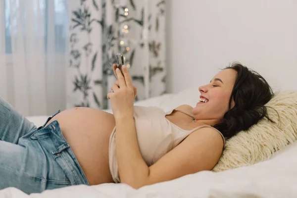 Joyeux charmant femme enceinte en utilisant le téléphone mobile. Femme enceinte. — Photo