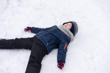 Küçük çocuk karla oynuyor. Kış tatili.