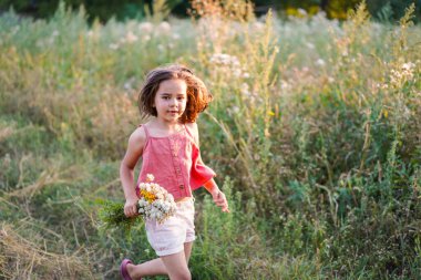 Tarlada çiçekli küçük bir kızın portresi. Yaşam biçimi