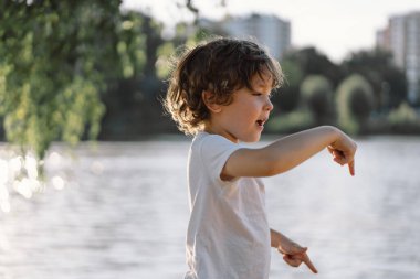 Nehir kenarındaki doğada oynayan sevimli bir çocuğun portresi..