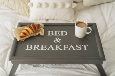 Kruvasan tepsisi ve beyaz temiz yatakta bir fincan kahve. Dikkatli ve sakin bir yaşam..