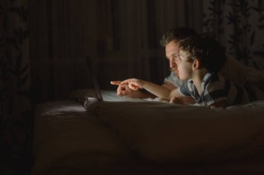 Baba ve oğul geceleri evde yatak odasında dizüstü bilgisayar kullanıyorlar. Teknoloji konsepti