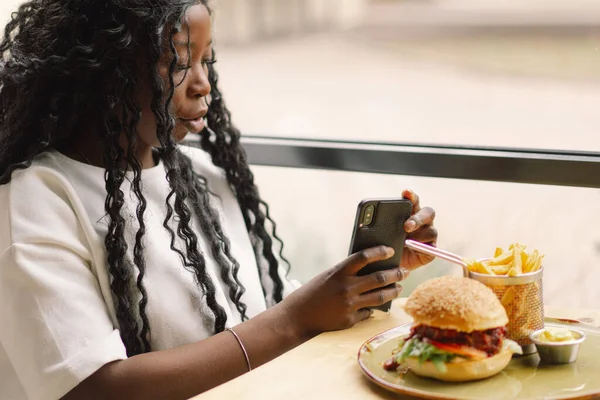 Mujer africana usando el teléfono en la cafetería. Personas y tecnología — Foto de Stock