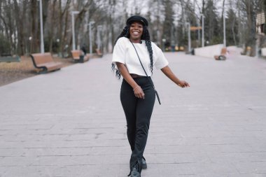 Neşeli siyah tenli kızın resmi. Şehir parkında yürüyen afro kız. Yaşam biçimi