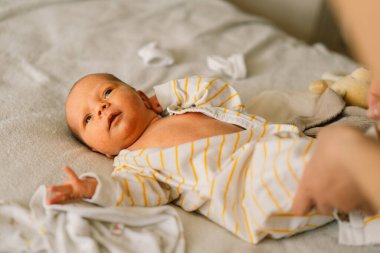 Annem yeni doğmuş şirin bir bebeği tulumla giydiriyor..