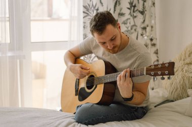 Adam evdeki bir odada akustik gitar çalıyor. Hobi bir müzisyen. Evdeki hayat
