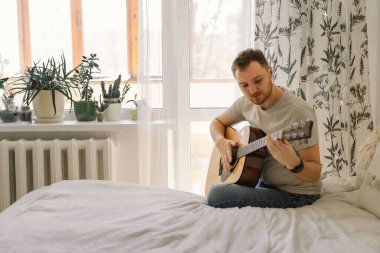 Adam evdeki bir odada akustik gitar çalıyor. Hobi bir müzisyen. Evdeki hayat