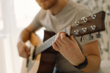 Adam evdeki bir odada akustik gitar çalıyor. Hobi. Müzisyen..
