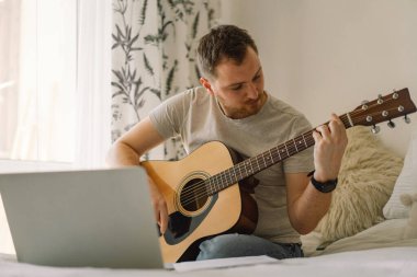 Adam online derste akustik gitar çalıyor. Hobi bir müzisyen. Evdeki hayat