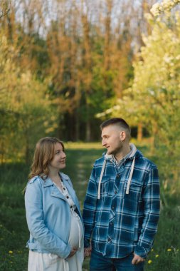 Bahar bahçesinde sarılan genç ve güzel bir çift. Hamilelik kavramı