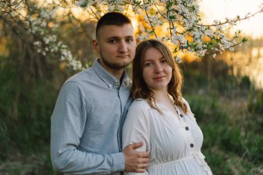 Bahar bahçesinde sarılan genç ve güzel bir çift. Hamilelik kavramı