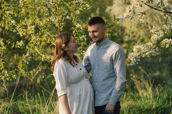 Bahar bahçesinde sarılan genç ve güzel bir çift. Hamilelik kavramı