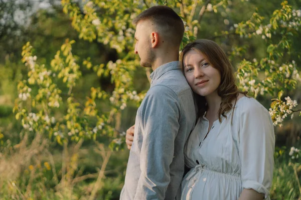 Bahar bahçesinde sarılan genç ve güzel bir çift. Hamilelik kavramı