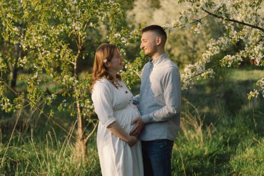 Bahar bahçesinde sarılan genç ve güzel bir çift. Hamilelik kavramı