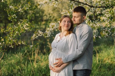 Bahar bahçesinde sarılan genç ve güzel bir çift. Hamilelik kavramı
