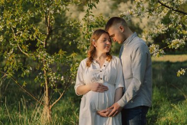 Bahar bahçesinde sarılan genç ve güzel bir çift. Hamilelik kavramı