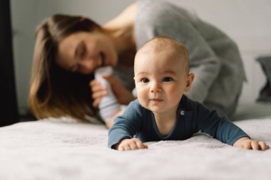 Genç bir anne, küçük bir bebekle oynuyor. Emziren bir bebeğin annesi. Mutlu annelikler. Aile evdedir. Mutlu bir anne ve çocuğun portresi..
