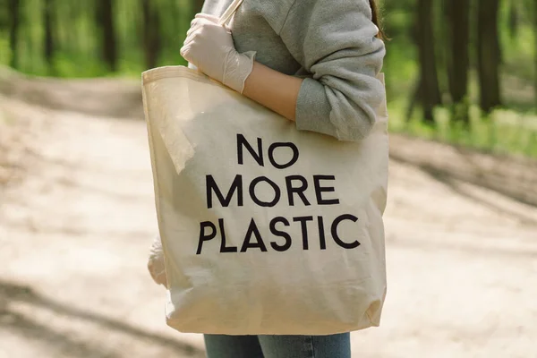 Vrijwilligersvrouw wordt gereinigd in het bos. Vrouw verzamelt plastic. — Stockfoto