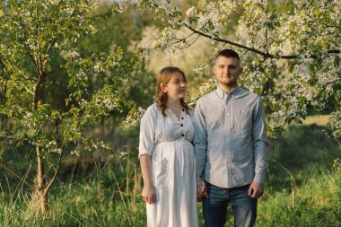 Bahar bahçesinde sarılan genç ve güzel bir çift.